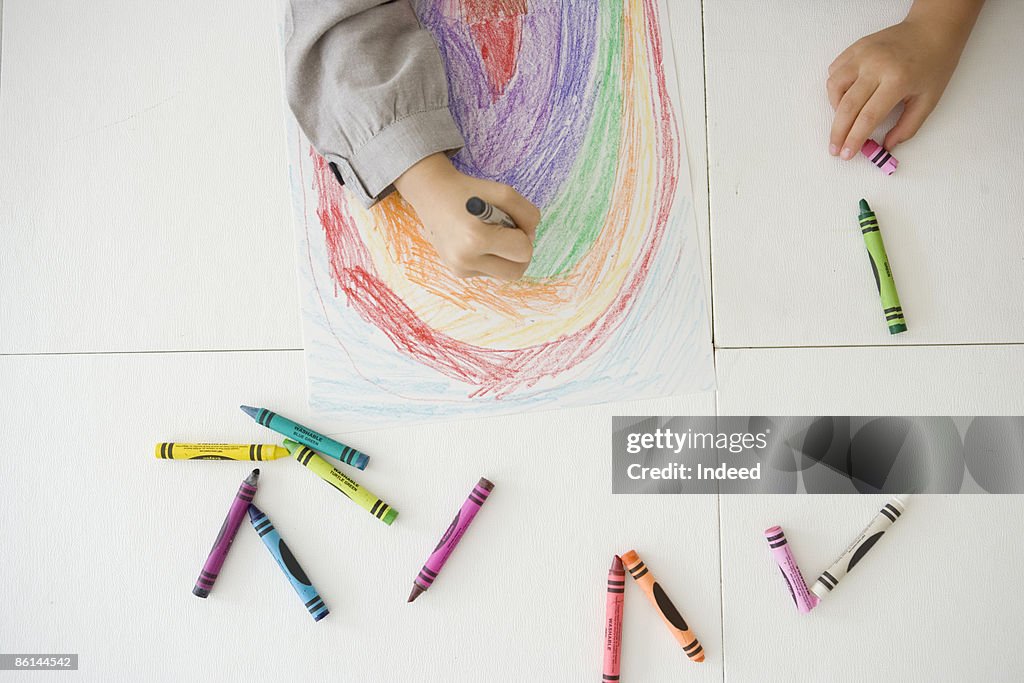 Girl drawing rainbow with crayon, 