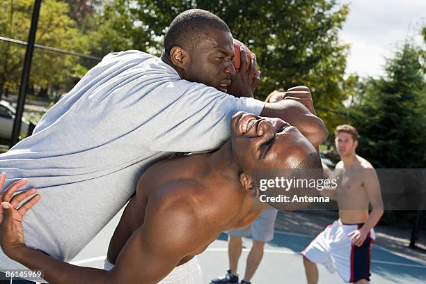 a basketball player fouling another player - man tackling stock pictures, royalty-free photos & images