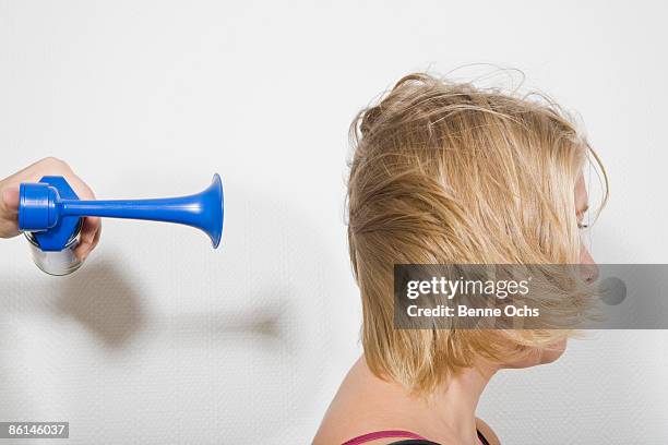 a woman with an air horn being blown at the back of her head - horn press stock pictures, royalty-free photos & images