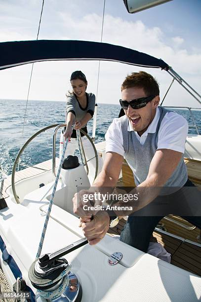 a couple adjusting the rigging on a yacht - cabestano foto e immagini stock