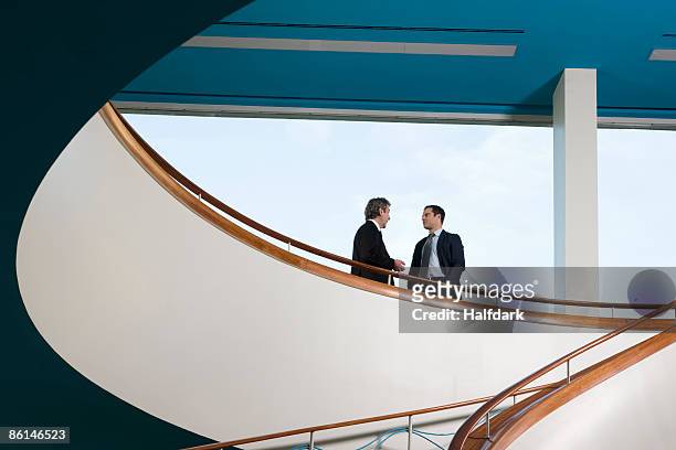 two businessmen standing on a balcony and talking - architektur stock-fotos und bilder