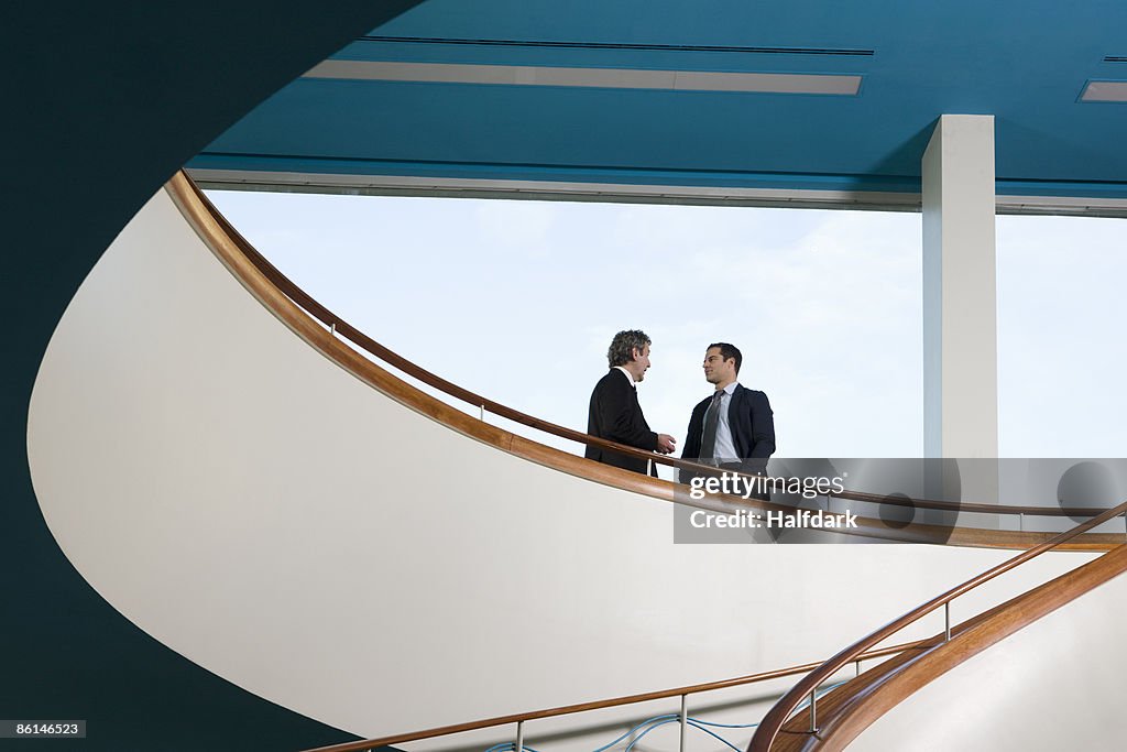 Two businessmen standing on a balcony and talking