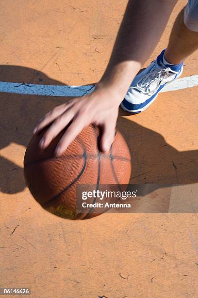 a human hand dribbling a basketball - basketball shoe stock-fotos und bilder