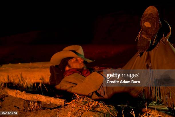 a cowboy illuminated by a campfire while sleeping - cowboy sleeping stock pictures, royalty-free photos & images