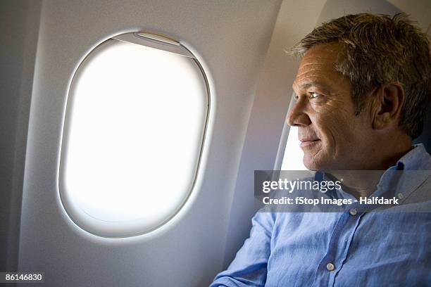 a male passenger on a plane looking through window - cabine de passageiros - fotografias e filmes do acervo