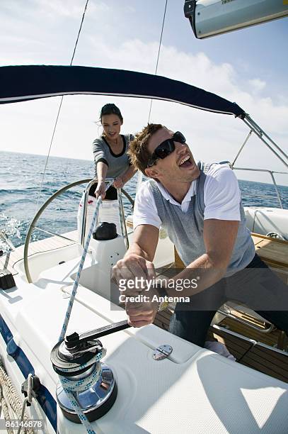 a couple adjusting the rigging on a yacht - cabestano foto e immagini stock