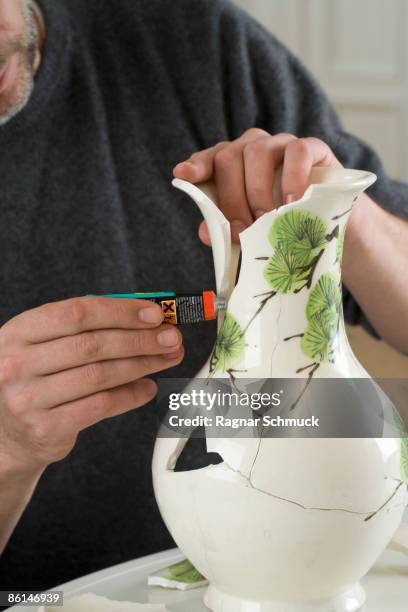 a man repairing a broken vase - broken vase stock pictures, royalty-free photos & images