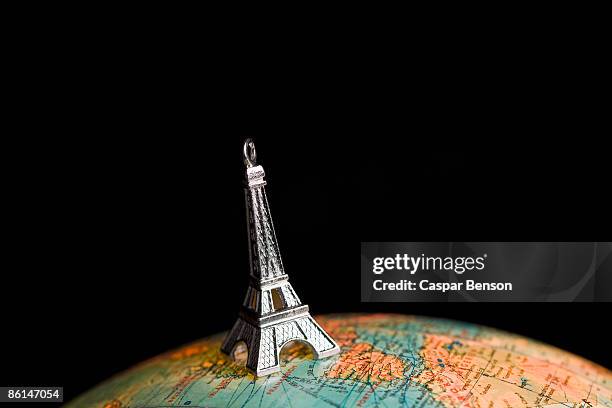 a statue of the eiffel tower on top of a globe - top of the world photos et images de collection