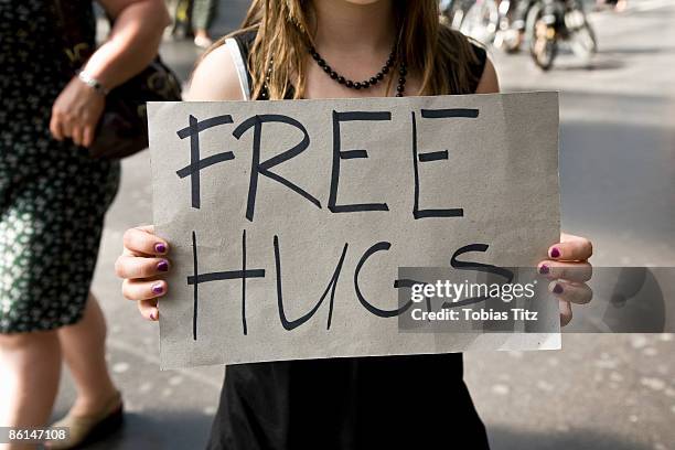 a young woman holding a sign saying free hugs - vrijgevigheid stockfoto's en -beelden