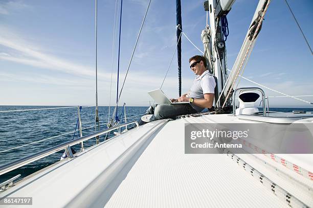 a man using a laptop on a yacht - mast sailing stock-fotos und bilder