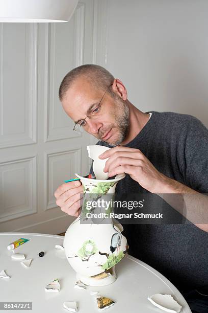 a man repairing a broken vase - broken vase stock pictures, royalty-free photos & images