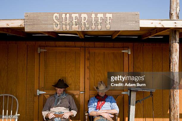 two cowboys sitting outside the office of the sheriff - cowboy sleeping stock pictures, royalty-free photos & images