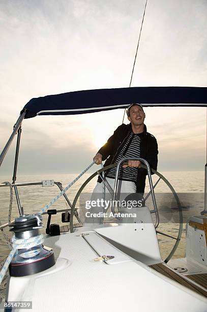 a man at the helm of a yacht adjusting the rigging - cabestano foto e immagini stock