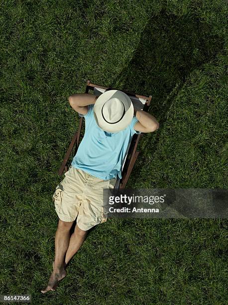 a man sitting on a sun lounger - sun lounger 個照片及圖片檔