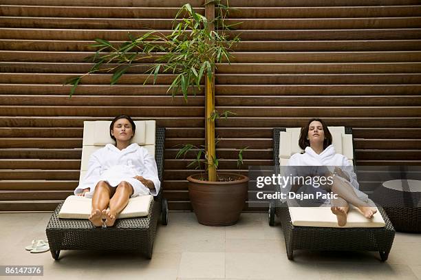 two women lying in lounge chairs - robe stock pictures, royalty-free photos & images