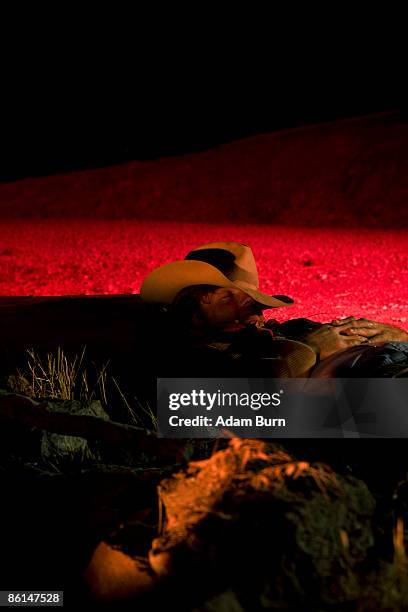 a cowboy illuminated by a campfire while sleeping - cowboy sleeping stock-fotos und bilder