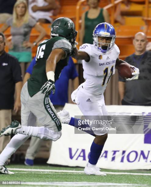 JaQuan Blackwell of the San Jose State Spartans stiff arms Kalen Hicks of the Hawaii Rainbow Warriors during the third quarter of their game at Aloha...
