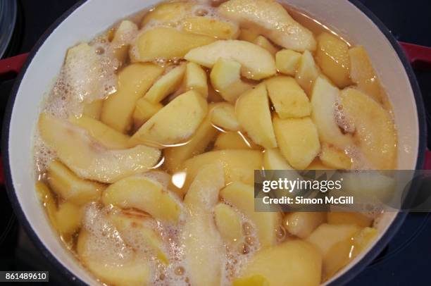 chopped quince slices being brought to the boil in a large stock pot - quitte stock-fotos und bilder