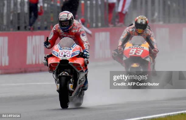 Ducati rider Andrea Dovizioso of Italy flashes thumb-up while receiving a checkered flag ahead of Honda rider Marc Marquez of Spain during the MotoGP...