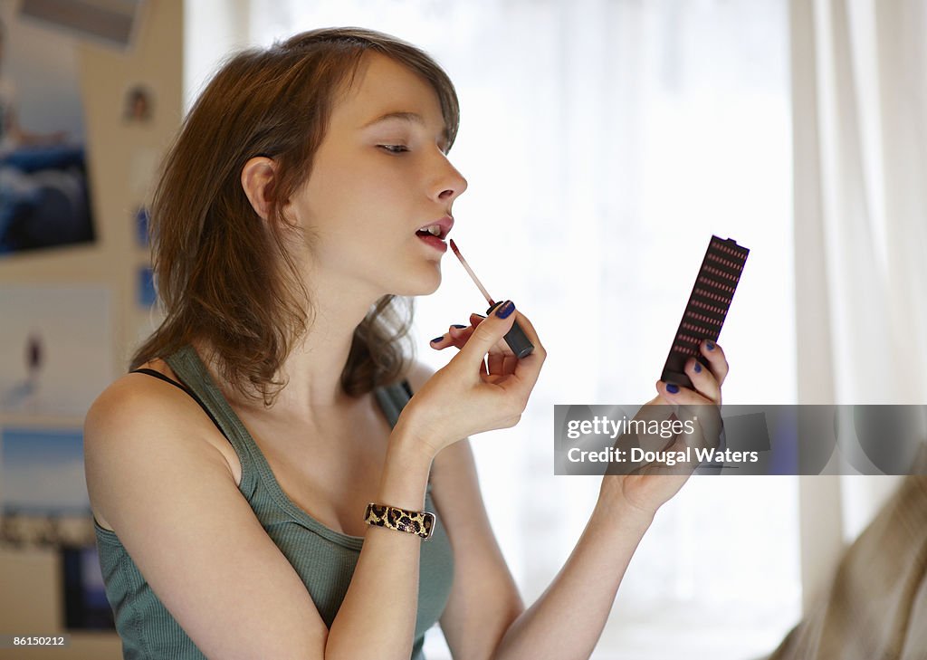 Young woman putting on make up.