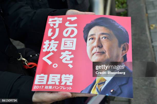 An attendee holds a pamphlet featuring a portrait of Shinzo Abe, Japans prime minister and president of the Liberal Democratic Party , during an...