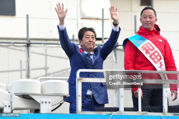Shinzo Abe, Japans prime minister and president of the Liberal Democratic Party , center, waves as he stands next to Yoshiaki Wada, a member of the...