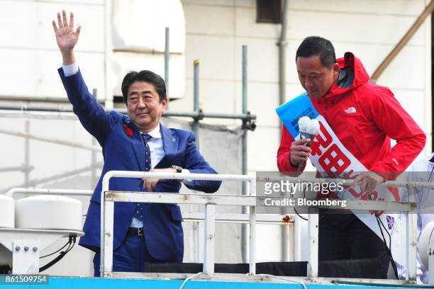 Shinzo Abe, Japans prime minister and president of the Liberal Democratic Party , left, waves as he stands next to Yoshiaki Wada, a member of the...