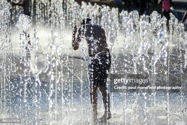 boy playing in shower fountain - heatwave stockfoto's en -beelden