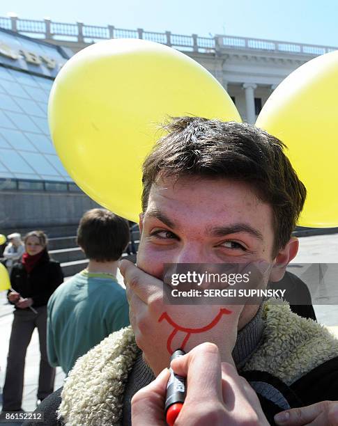 Student holds his hand to his mouth with a smile and tongue painted on his hand during an action in Independence Square in Kiev called "Smile...