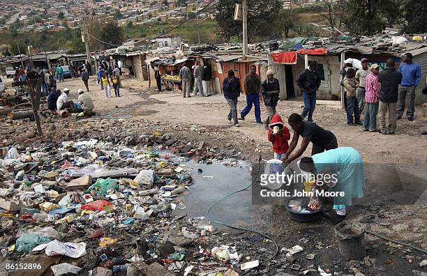 Women wash and a boy drinks from a common water tap near a polling station on April 22, 2009 in the Sweetla Squatter Camp near Alexandra Township,...