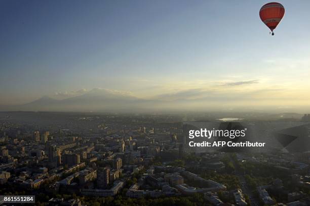 Hot air balloon flies over Yerevan on October 14, 2017 during the balloon festival in honor of the 2799th birthday of the Armenian capital, as Mount...