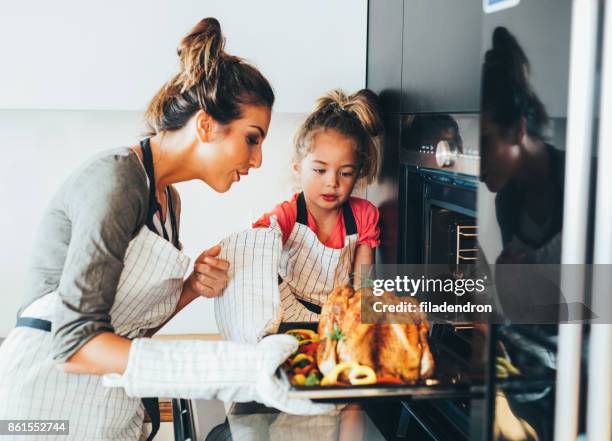 mother taking the dinner out of the oven - chicken roasting oven stock pictures, royalty-free photos & images