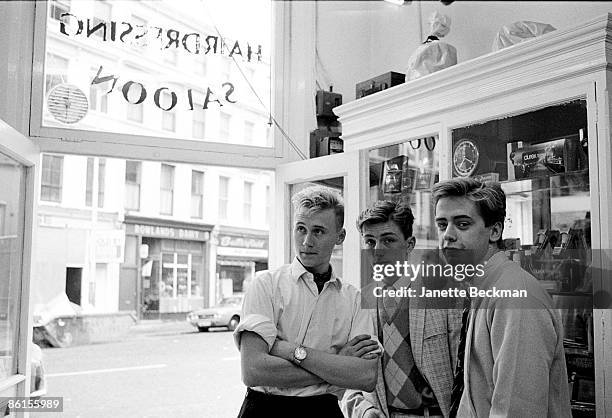 Portrait of pop group Haircut 100 as they pose inside the door of a 'Hairdressing Saloon,' London, England, 1981. Pictured are, from left, Graham...