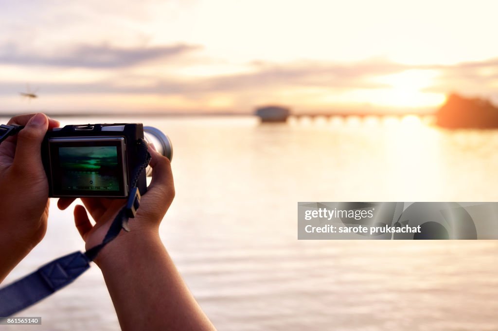 Digital camera  in boy hand  He shoots photo and nature background .