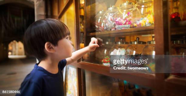 east asian young boy looking at colourful candy jars. - china east asia stock-fotos und bilder