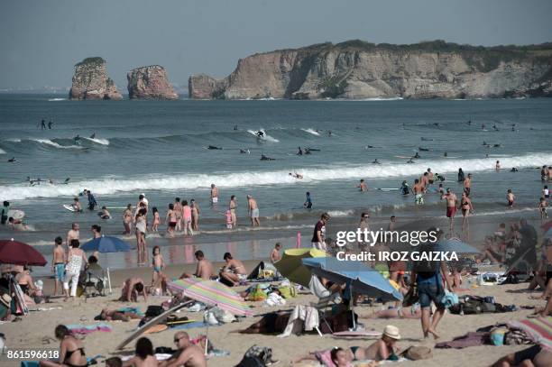 People enjoy the sun at the Grande Plage beach in Hendaye, southwestern France, on October 15, 2017 as unusually warm autumnal temperatures reach 30...