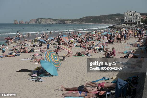 People enjoy the sun at the Grande Plage beach in Hendaye, southwestern France, on October 15, 2017 as unusually warm autumnal temperatures reach 30...