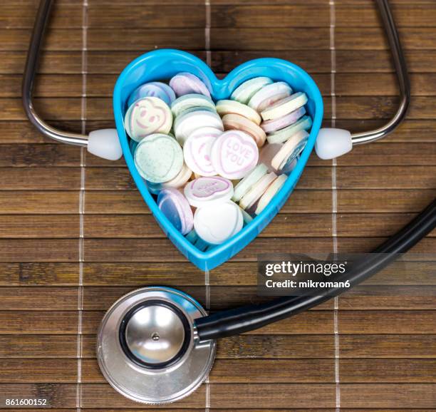 stethoscope and multi colored heart shape candy with text in heart shape container - doctor emoticon stock pictures, royalty-free photos & images