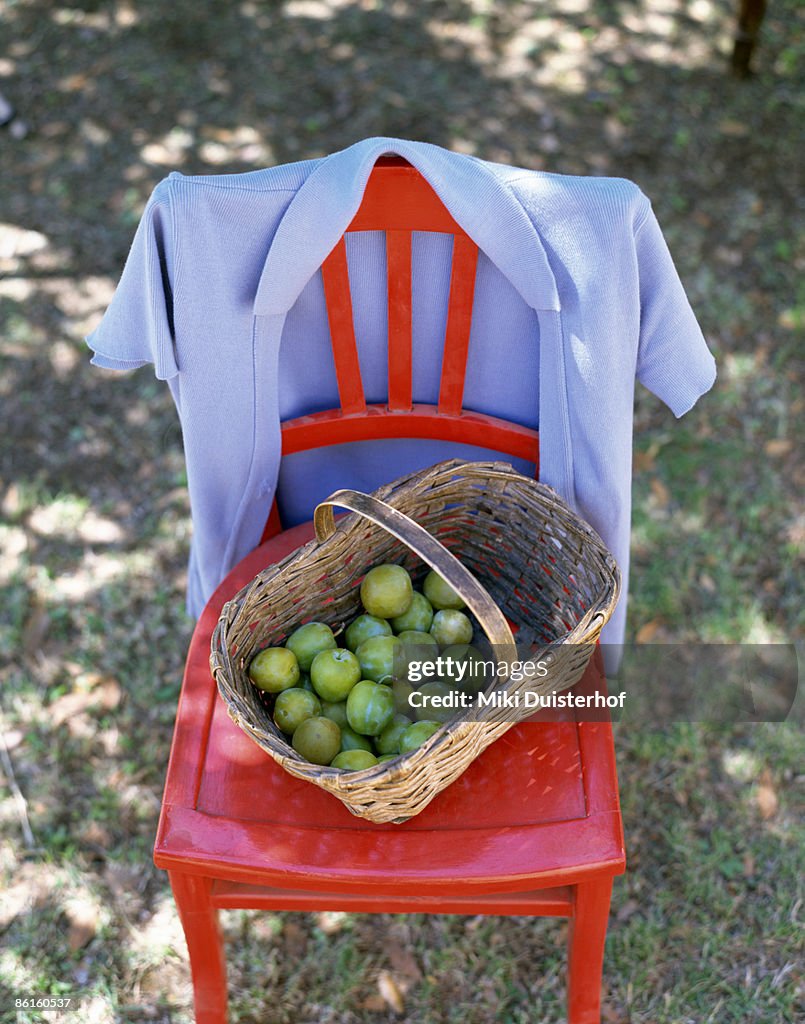 Red chair with basket of green plums