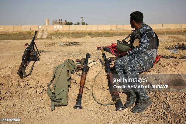 Member of the Iraqi forces sits on a river bank across from Kurdish peshmerga positions on October 15 on the southern outskirts of Kirkuk. The...
