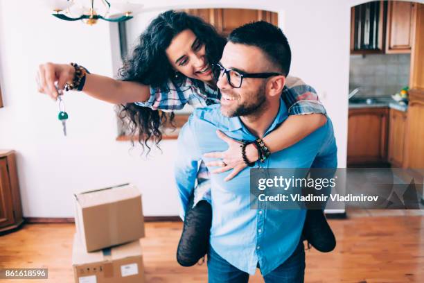 young couple holding keys of new apartment - home ownership keys stock pictures, royalty-free photos & images
