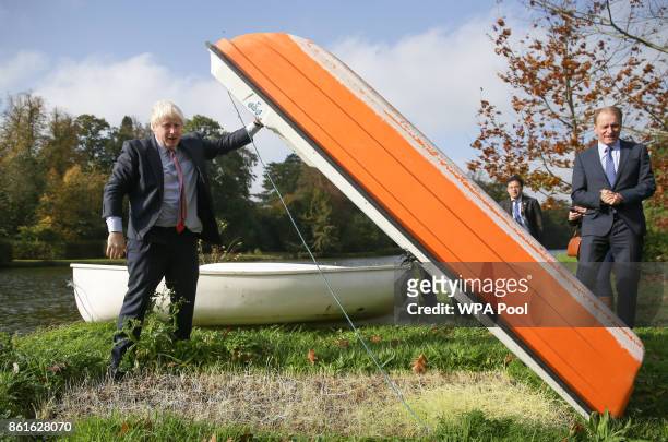 Britain's Foreign Secretary Boris Johnson lifts a small boat before going out onto a boating lake in a rowing boat with Czech Republic's Deputy...