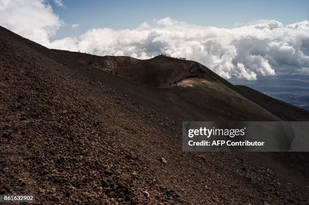 People hike on September 21, 2017 on the Mount Etna volcano on the Italian island of Sicily. / AFP PHOTO / Guillaume BAPTISTE