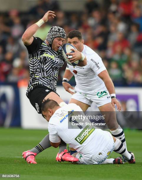 Ospreys player Dan Lydiate is tackled by Raphael Chaume during the European Rugby Champions Cup match between Ospreys and ASM Clermont Auvergne at...