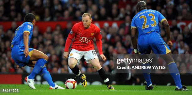 Manchester United's English forward Wayne Rooney vies with Portsmouth's English defender Sol Campbell and Portsmouth's English defender Glen Johnson...