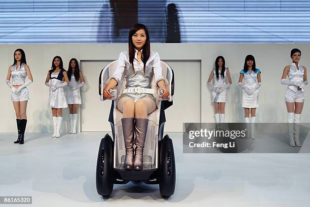 Model drives a Toyota i-REAL concept car on display during a special trade visitors opening of the Auto Shanghai 2009 at Shanghai New International...