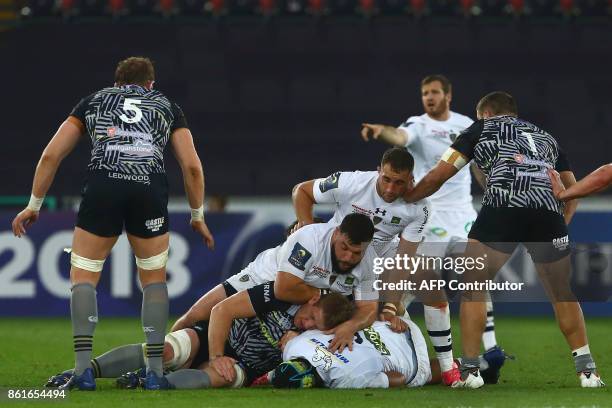 Ospreys' Welsh lock Bradley Davies is tackled by Clermont's prop Rabah Slimani , Clermont's French scrum-half Morgan Parra and Clermont's French lock...