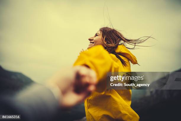 twee wandelaars in de natuur hand in hand - geel jak stockfoto's en -beelden