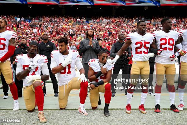 Waun Williams, Arik Armstead and Eli Harold of the San Francisco 49ers kneel while holding their hands over their chest during the U.S. National...