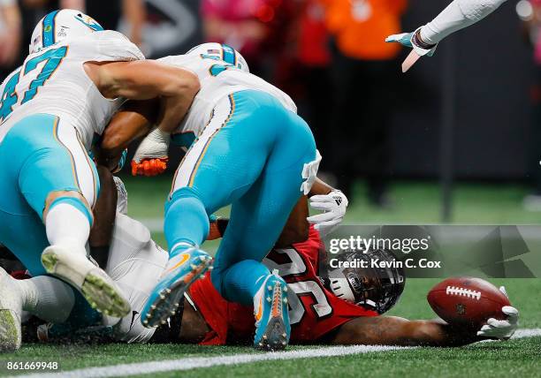 Tevin Coleman of the Atlanta Falcons stretches for a touchdown against Kiko Alonso and Nate Allen of the Miami Dolphins at Mercedes-Benz Stadium on...